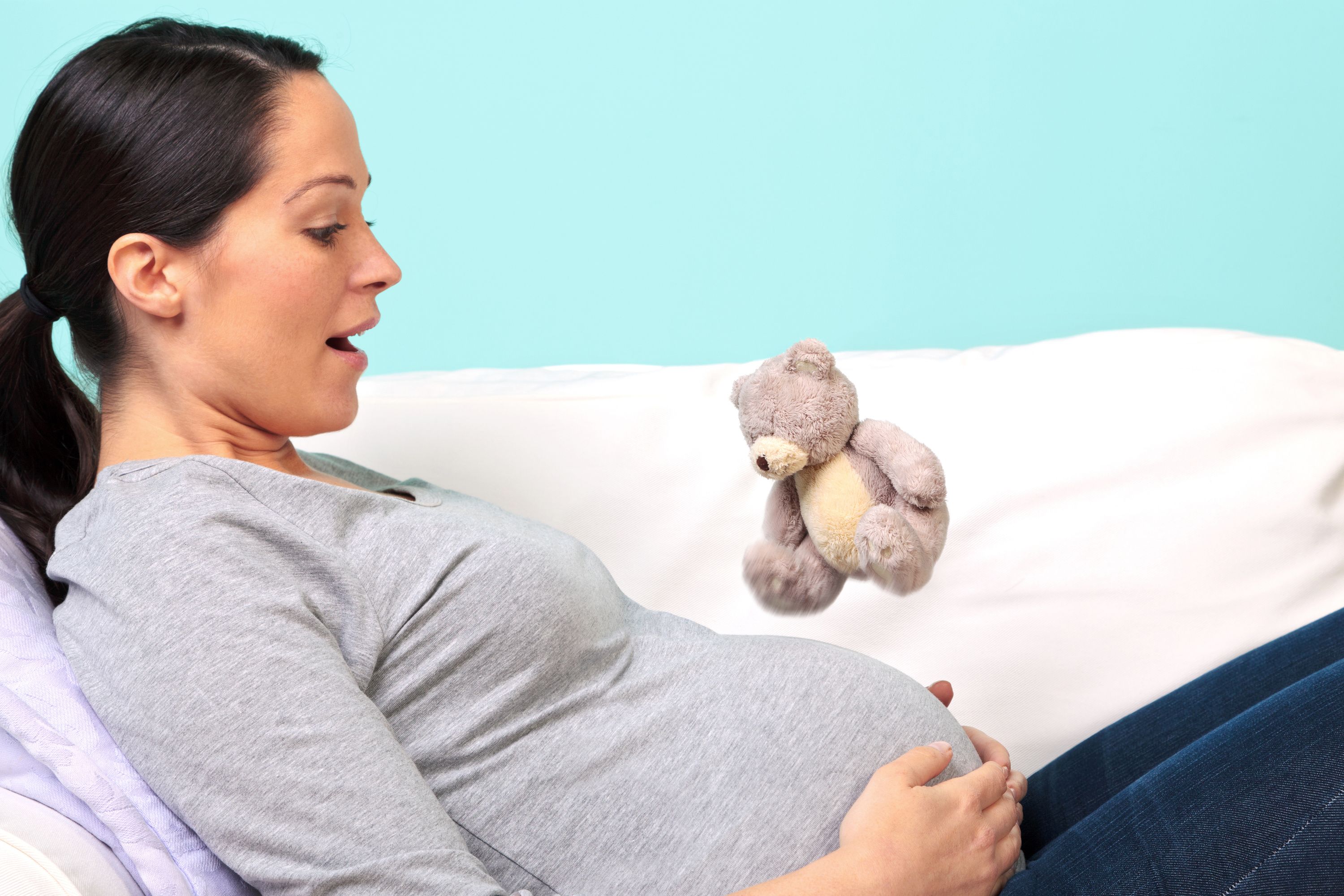Schwangere sitzt auf dem Sofa und hält sich den Bauch