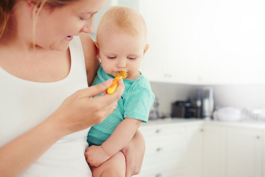 Mutter füttert Baby mit Brei