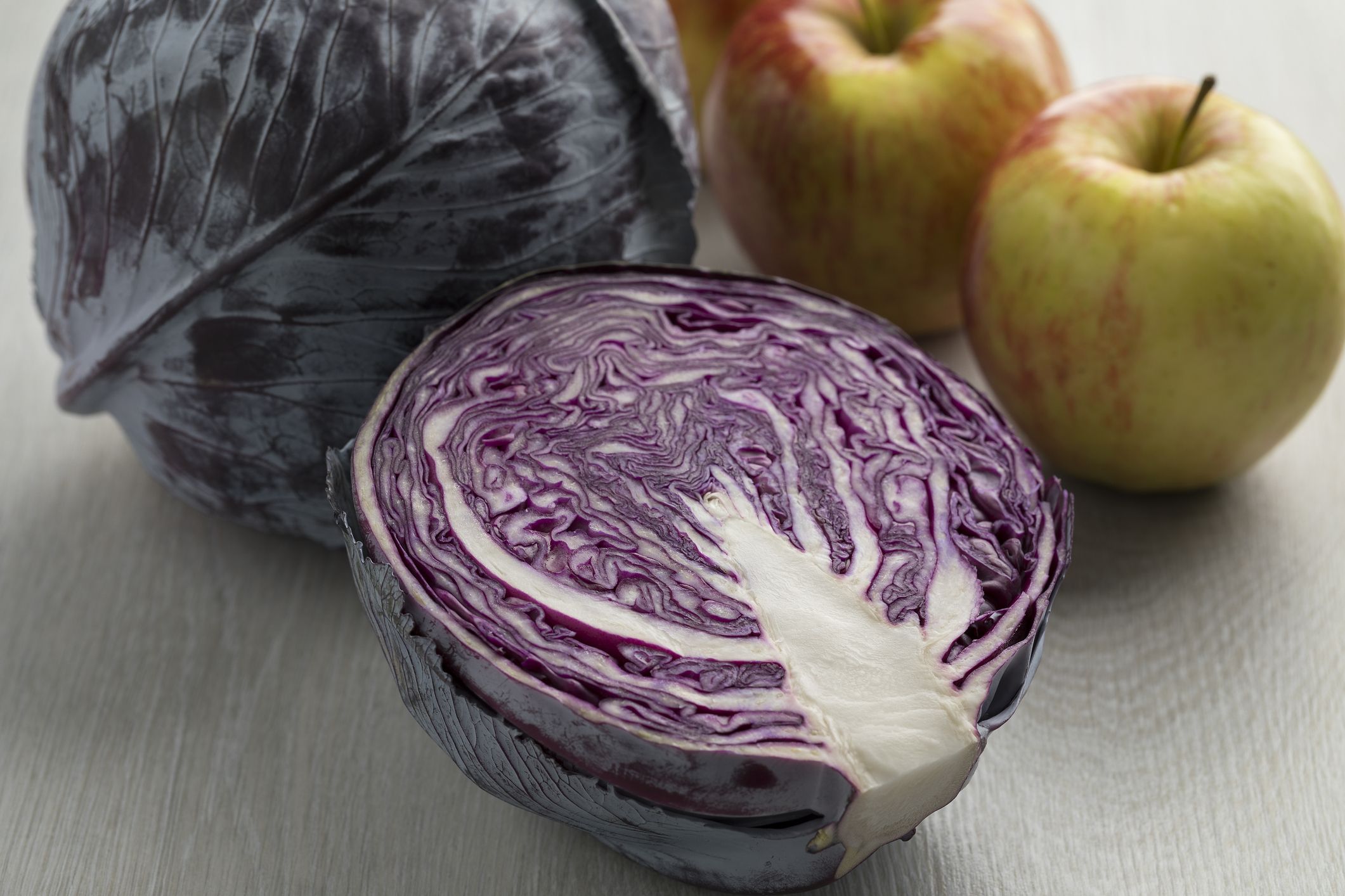 Aufgeschnittener und ganzer Rotkohl mit zwei Äpfeln