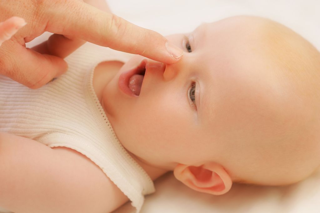 Zeigefinger tippt auf die Nase des Babys