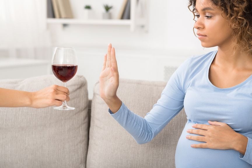 Schwangere Frau lehnt ein Glas Rotwein ab