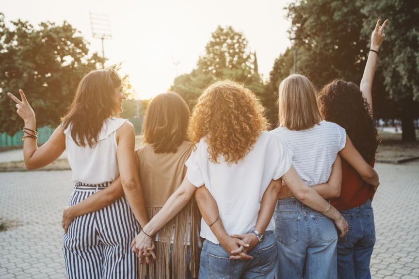 Gruppe junger Frauen von hinten mit Victory-Zeichen 