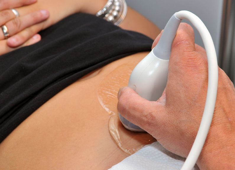 Ultraschallkopf auf dem Bauch einer Schwangeren
