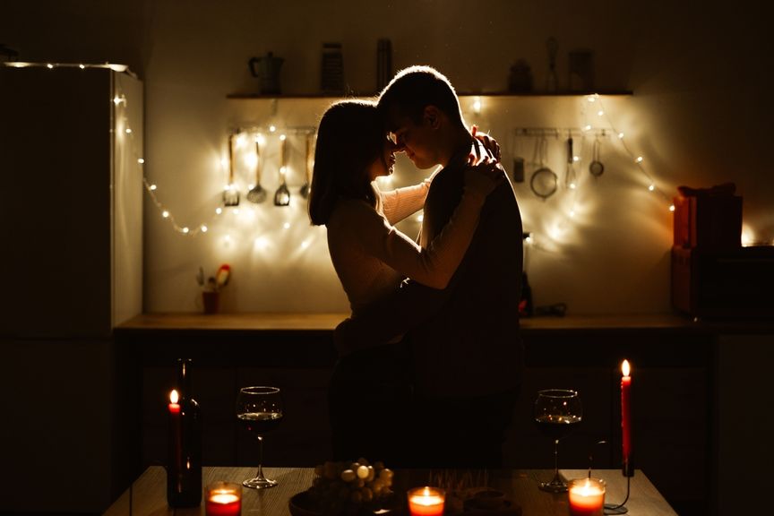 Liebespaar umarmt sich bei Kerzenschein in der Küche