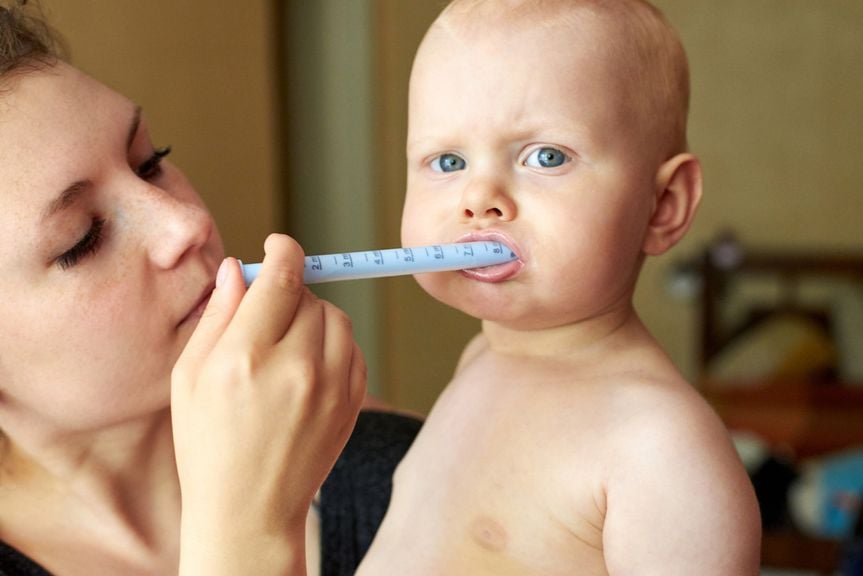 Mutter gibt ihrem Baby ein Medikament mit einer Spritze in den Mund