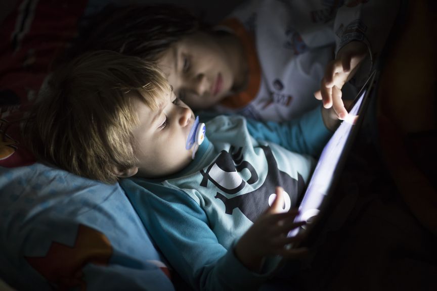 Kinder mit Tablet im Bett