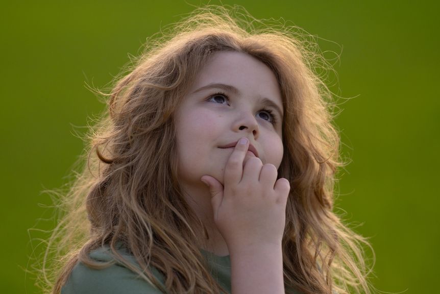 Kind mit wuscheligen Haaren blickt verträumt nach oben