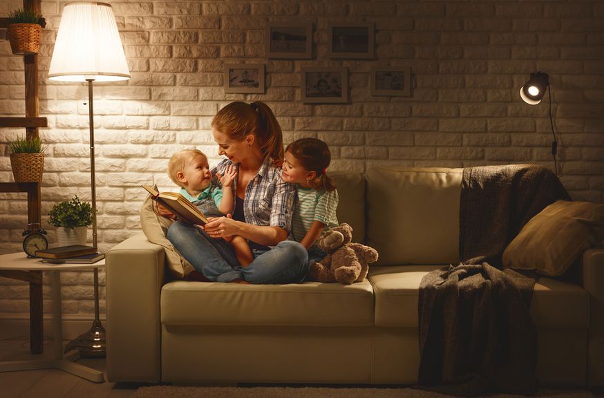 Mutter liest zwei Kindern etwas aus einem Buch vor