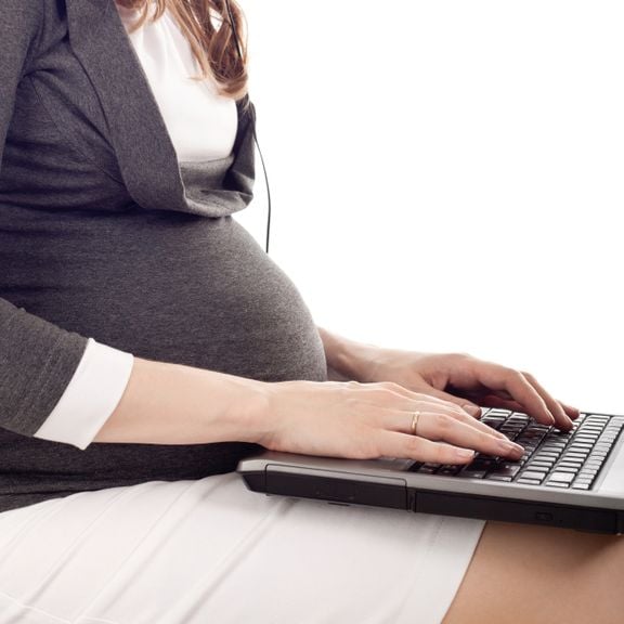 Schwangere mit Laptop auf den Knien