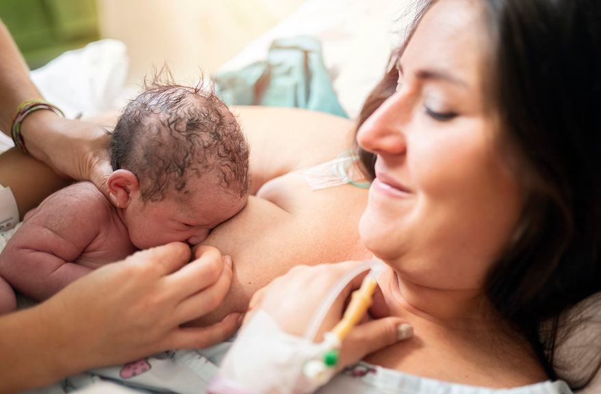 Mutter bekommt Hilfe beim ersten Anlegen nach der Geburt