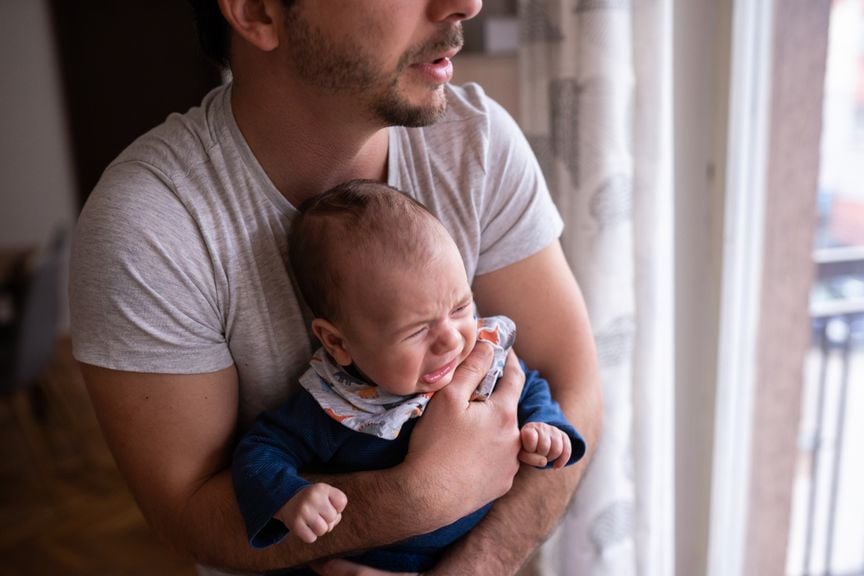 Vater trägt weinendes Baby