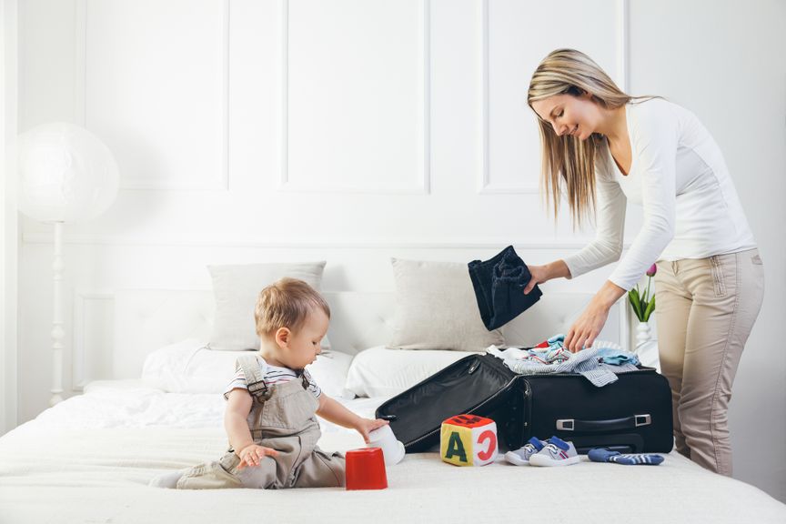 Mutter mit Baby packt Koffer für die Ferien