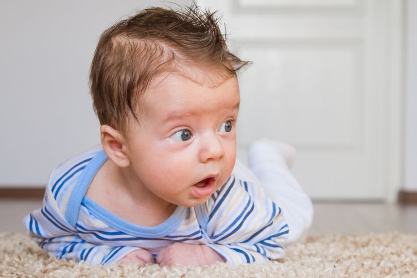Baby hält in Bauchlage den Kopf hoch