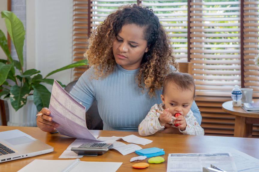 Frau mit Baby auf dem Schoss erledigt administrative Aufgaben