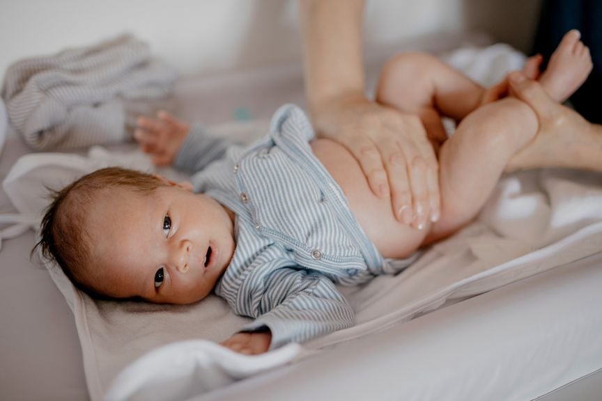 Hand der Mutter auf dem nackten Bauch ihres Säuglings