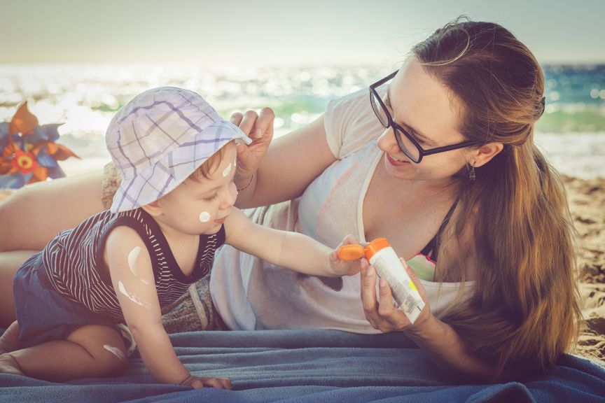 Mutter cremt Baby mit Sonnencreme ein