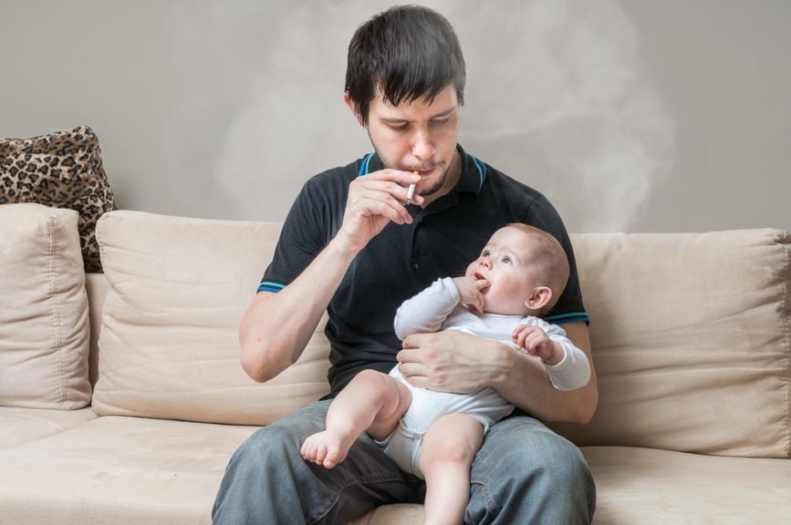 Vater mit Baby auf dem Schoss raucht