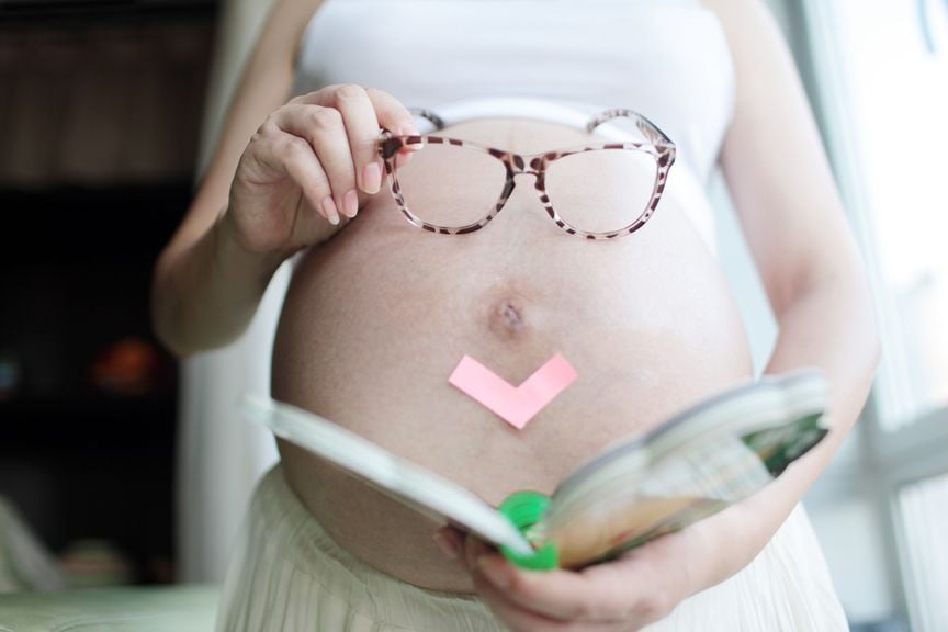 Schwangere mit Brille vor dem Bauch