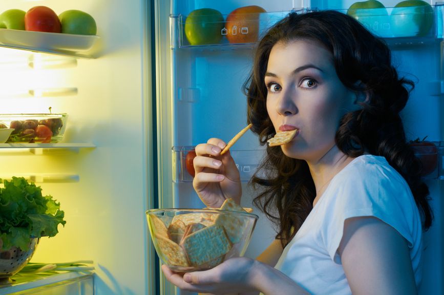 Frau isst direkt aus dem Kühlschrank