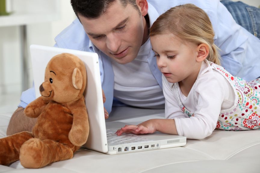 Vater und Tochter am Laptop mit Teddy 