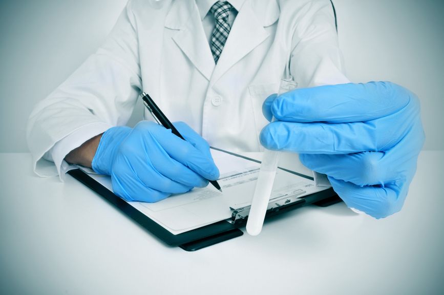 Arzt mit blauen Gummihandschuhen hält Reagenzglas mit tiefgefrorenem Sperma
