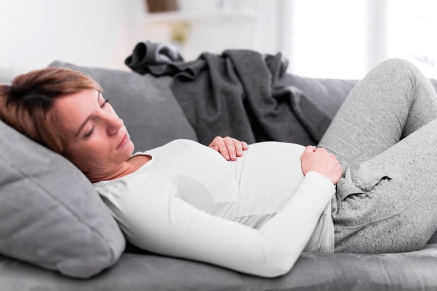 Schwangere liegt müde oder erschöpft auf dem Sofa