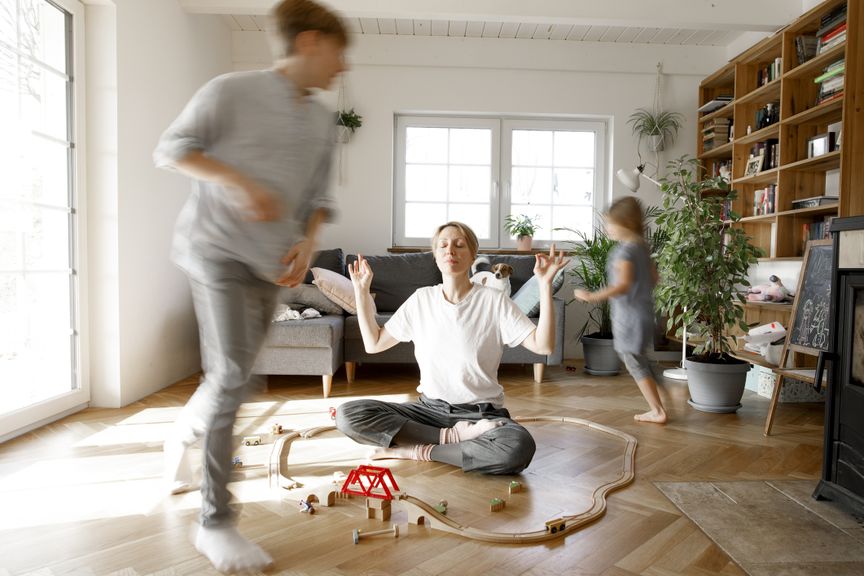 Kinder spielen im Wohnzimmer, Mutter macht Yoga