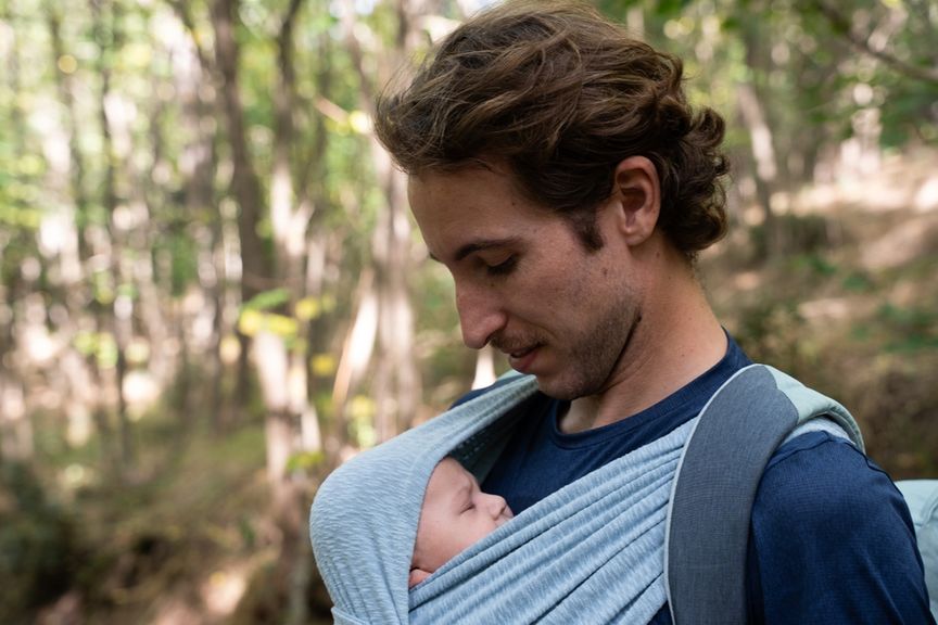 Mann mit schlafendem Baby im Tragetuch