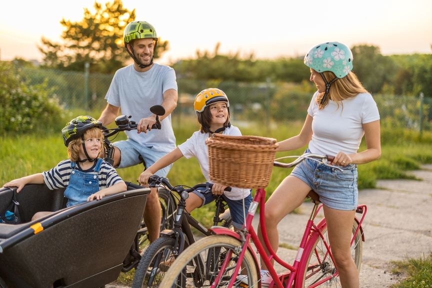 Familie mit Velohelmen und Fahrrädern auf einem Feldweg