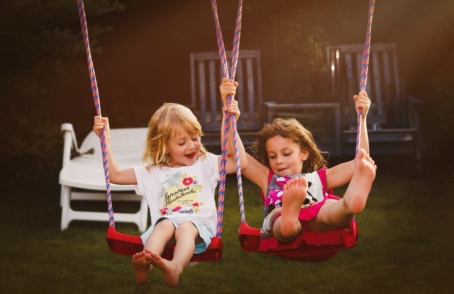 Zwei Kinder auf der Schaukel im Garten