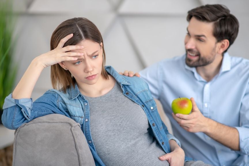 Mann bietet seiner schwangeren Frau einen Apfel an 