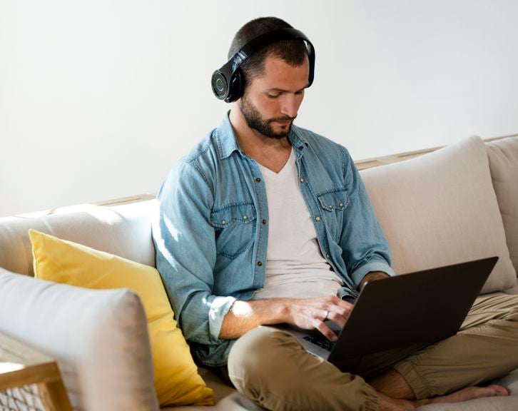 Mann mit Laptop auf dem Sofa