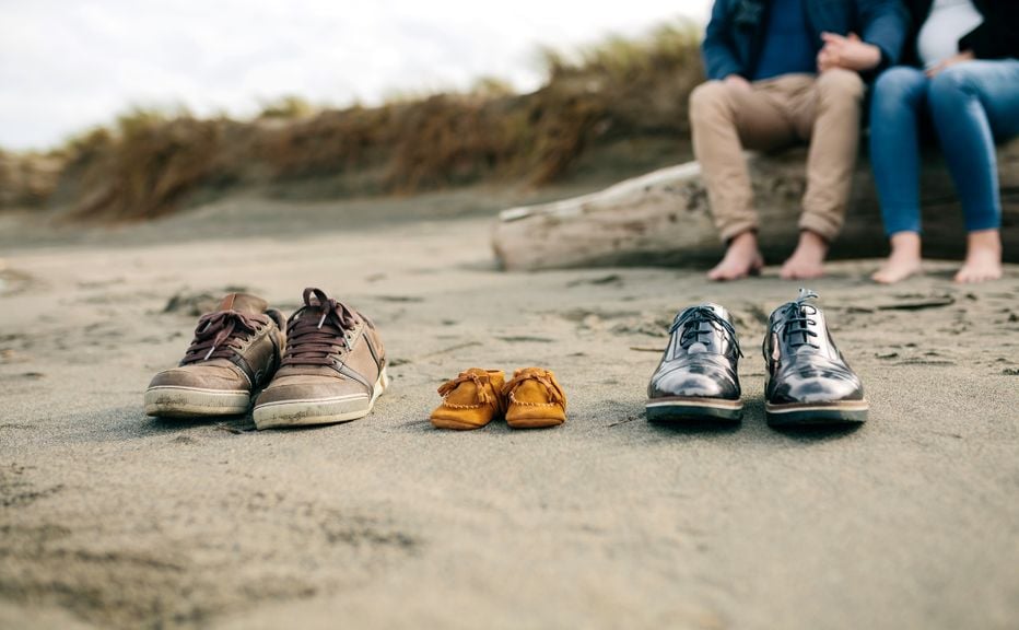 Schuhe von Eltern und Baby am Strand