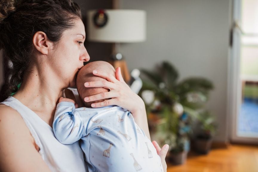 Mutter küsst Baby auf den Kopf