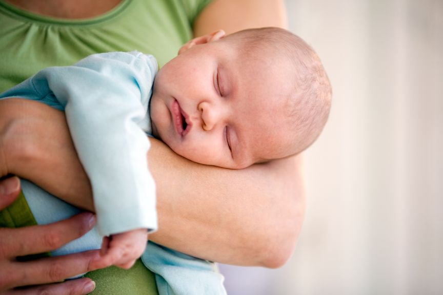 Säugling schläft auf dem Arm der Mutter