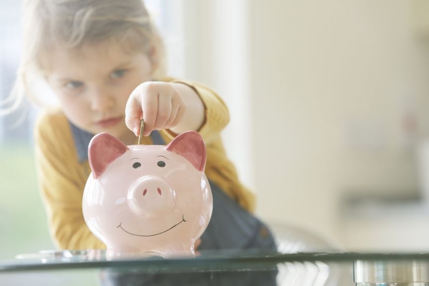 Mädchen gibt Münze in Sparschwein