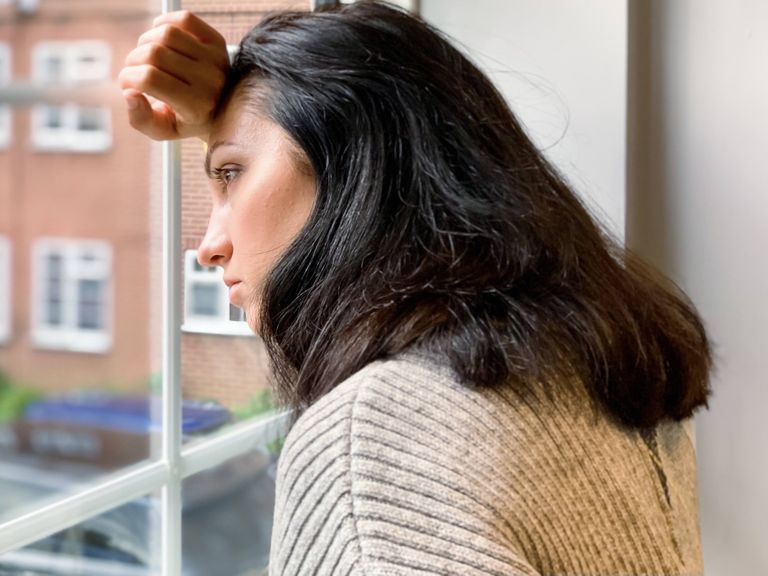 Frau schaut nachdenklich aus dem Fenster