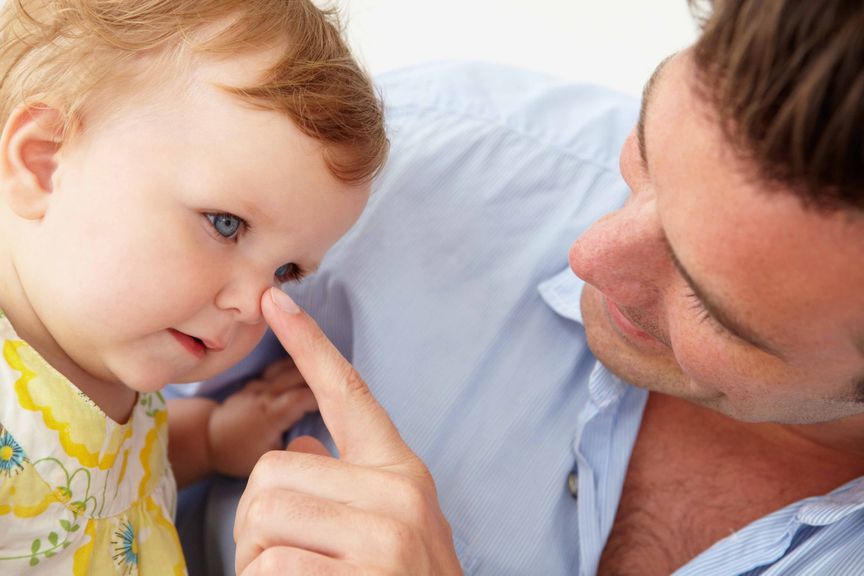 Vater stupst Baby mit dem Finger auf die Nase