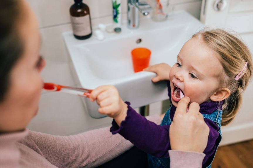 Mutter und Kind putzen sich gegenseitig die Zähne