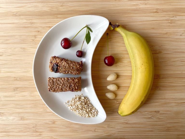 Hafer-Kirschen-Riegel mit Kirschen, Haferflocken, Mandeln und Banane auf einem halbmondförmigen Teller