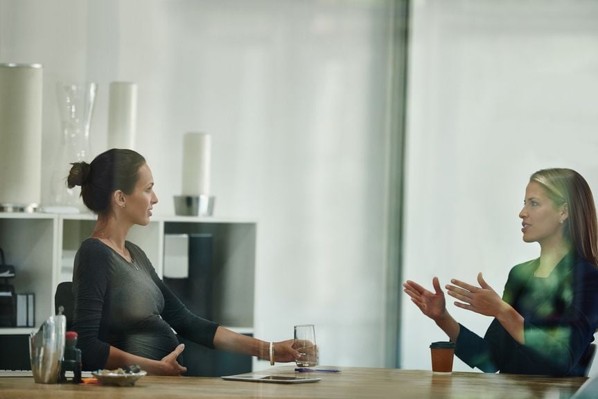 Schwangere im Büro bei der Besprechung mit einer Kollegin oder Vorgesetzten