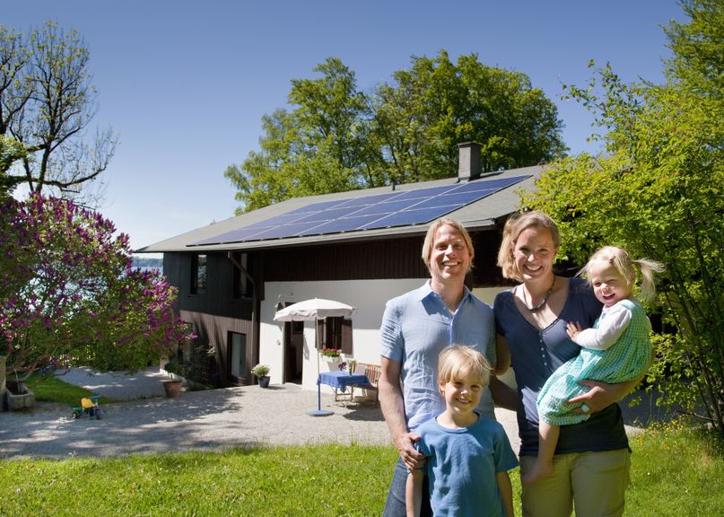 Familie mit zwei Kindern vor ihrem Haus