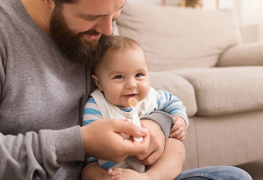 Vater füttert Baby mit Löffel