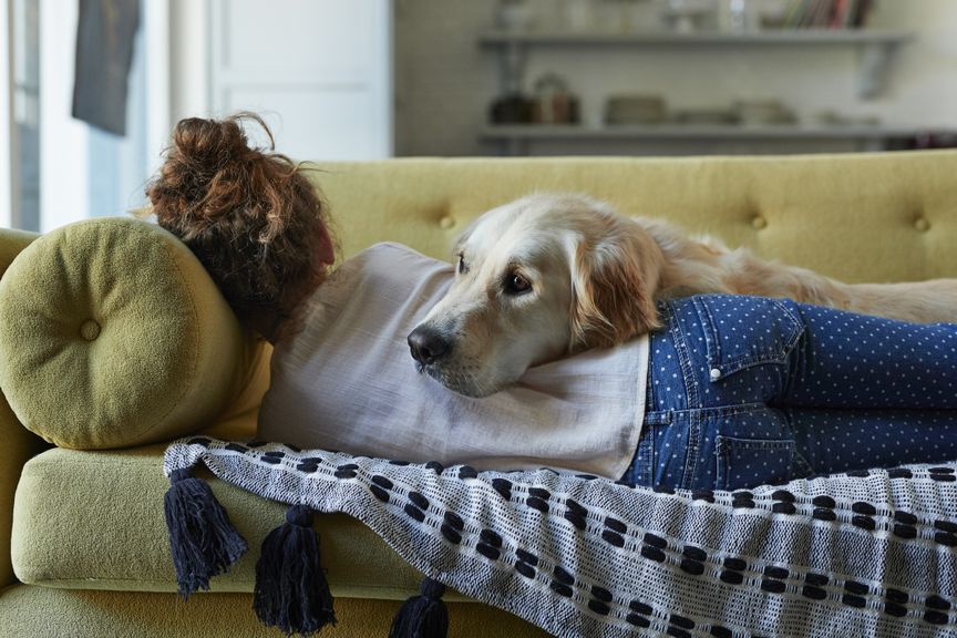 Kind liegt mit Hund auf dem Sofa