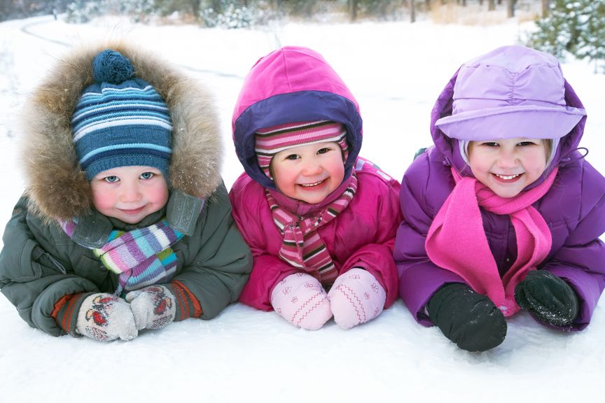 drei Kinder bäuchlings im Schnee