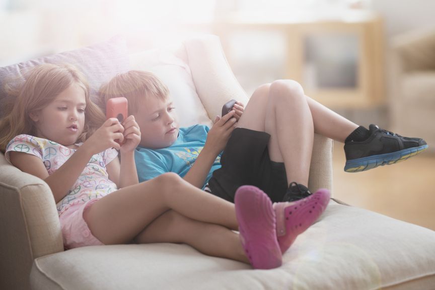 Zwei Kinder auf dem Sofa benutzen ihre Smartphones