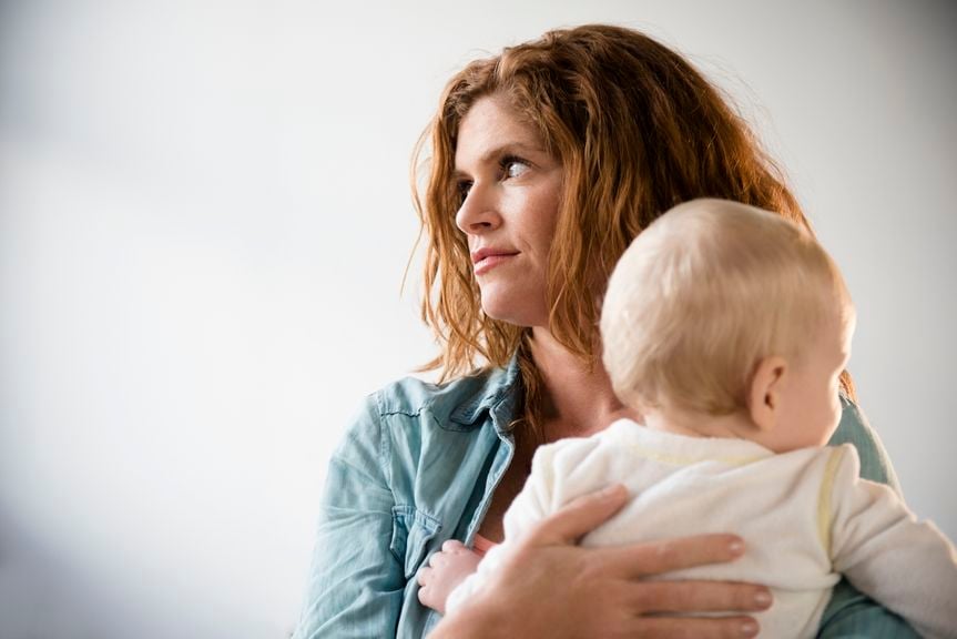 Frau mit Baby auf dem Arm verdreht die Augen