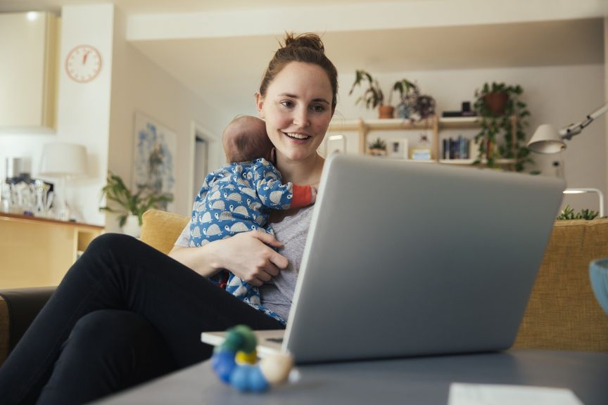 Mutter mit Neugeborenem am Laptop