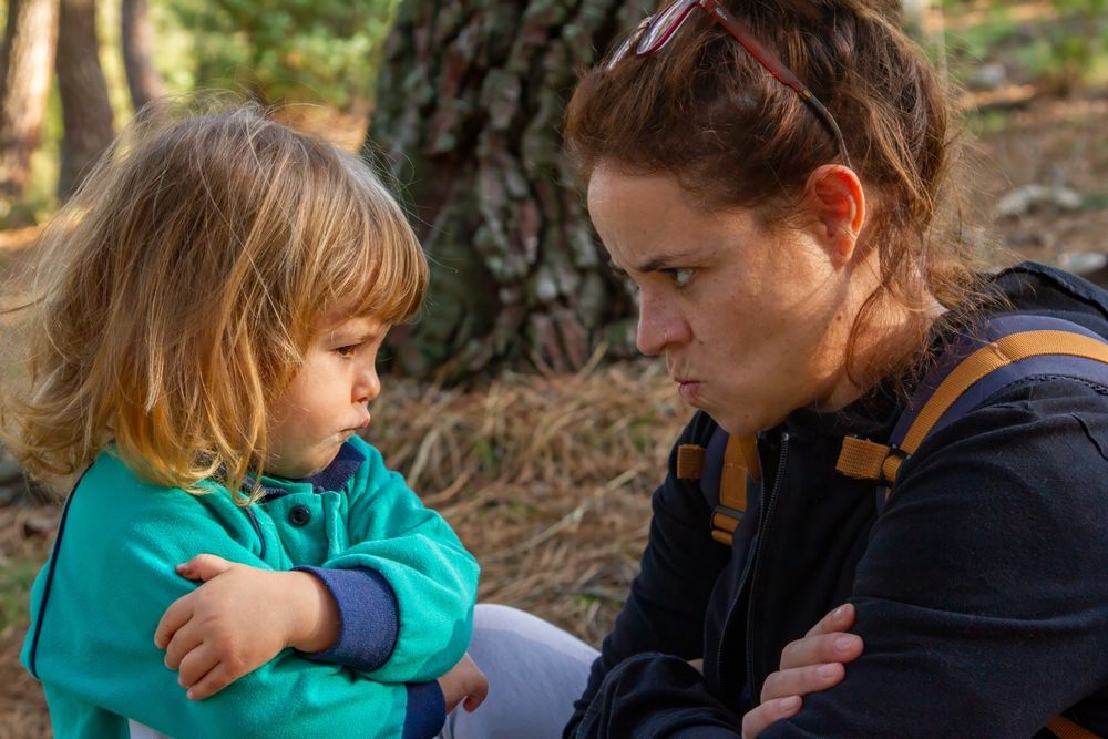 Mutter und Kleinkind blicken trotzig drein und verschränken die Arme