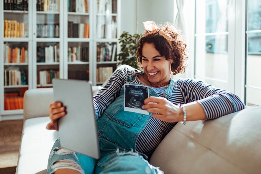 Schwangere hält Ultraschallbild vor ein Tablet